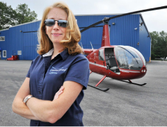 woman pilot posing before the red helicopter